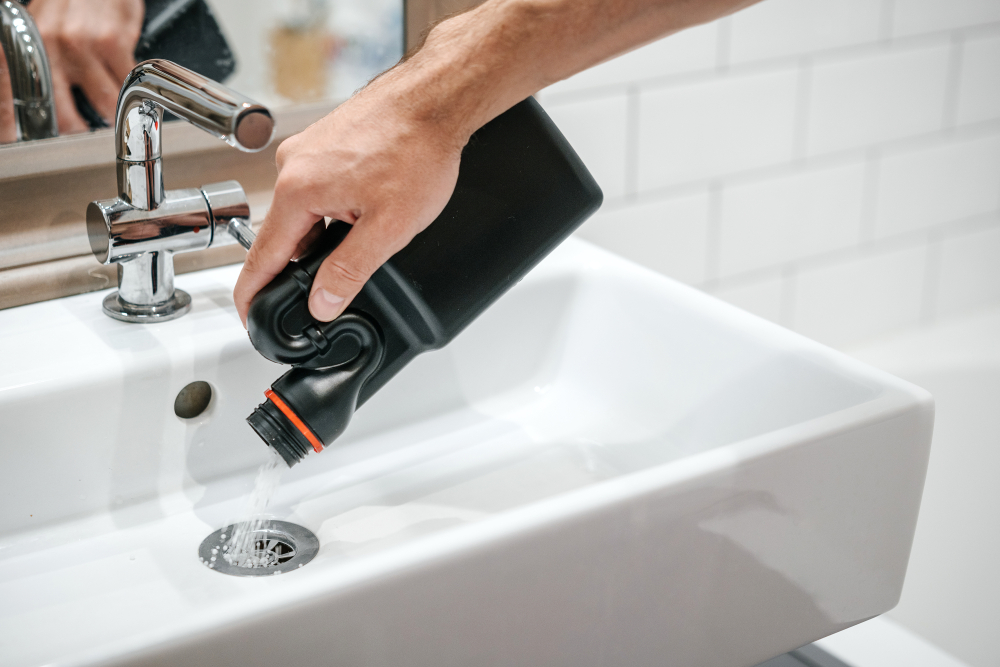 Person pouring liquid drain cleaning down a bathroom sink