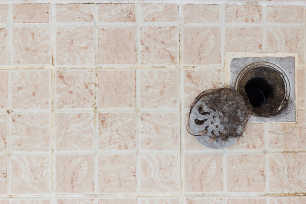 A clump of hair caught inside a shower drain.